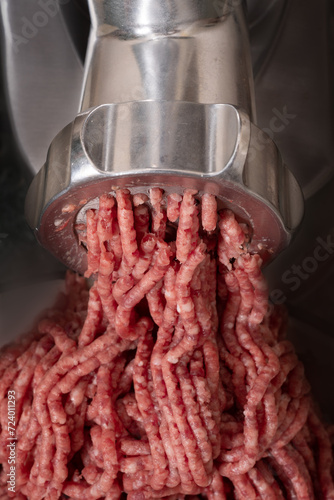 Minced meat coming out from modern electric grinder.