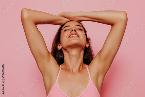 woman put her hands behind her head in against light pink studio background photo