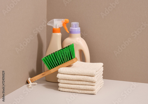 Green thick bristles in a wooden cleaning brush, detergent dispensers and clean shower towels.