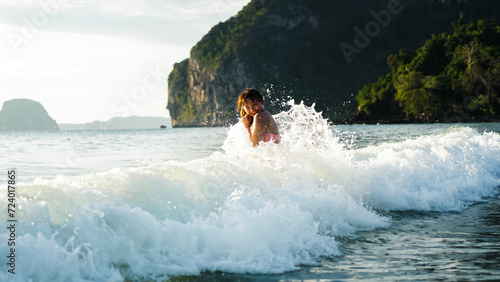 Splashing through the waves. Shot of laughing and smiling happiness asian women playing in wave at tropical beach.