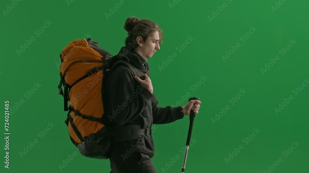 Side view of a hiker with a trekking stick. A man with a backpack on his back is walking in the studio on a green screen close up. The concept of hiking. Side view of a hiker with a trekking stick. A man with a backpack on his back is walking in the studio on a green screen close up. The concept of hiking.