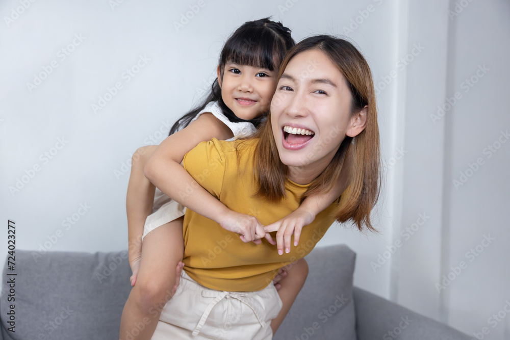 Asian daughter on a piggy back ride with her mother Asian daughter on a piggy back ride with her mother
