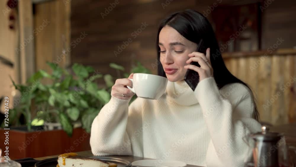 Happy girl calling with friends on smartphone while spending time at cafe drinking coffee Happy girl calling with friends on smartphone while spending time at cafe drinking coffee
