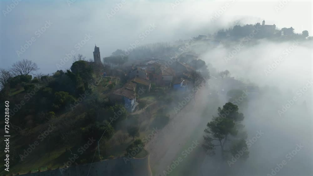 aerial view with the drone of the medieval village of Fiorenzuola di Focara immersed in the fog. We are in the San Bartolo park between Pesaro and Romagna aerial view with the drone of the medieval village of Fiorenzuola di Focara immersed in the fog. We are in the San Bartolo park between Pesaro and Romagna