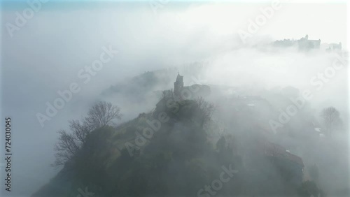 aerial view with the drone of the medieval village of Fiorenzuola di Focara immersed in the fog. We are in the San Bartolo park between Pesaro and Romagna photo