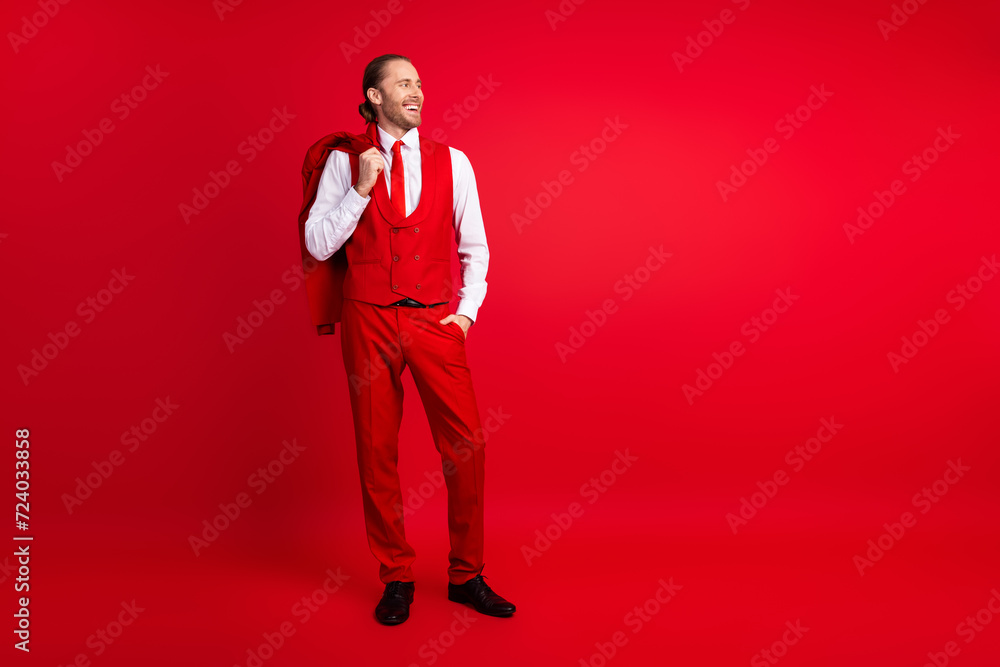 Full length photo of elegant young male hold jacket on shoulder empty space wear trendy classic garment isolated on red color background Full length photo of elegant young male hold jacket on shoulder empty space wear trendy classic garment isolated on red color background