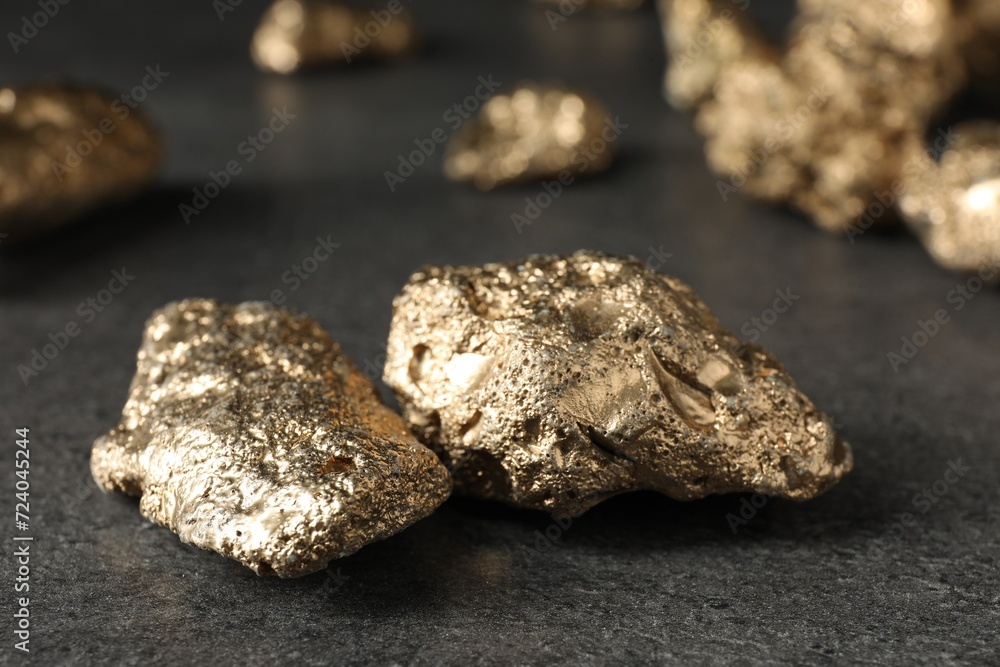 Shiny gold nuggets on grey textured surface, closeup Shiny gold nuggets on grey textured surface, closeup