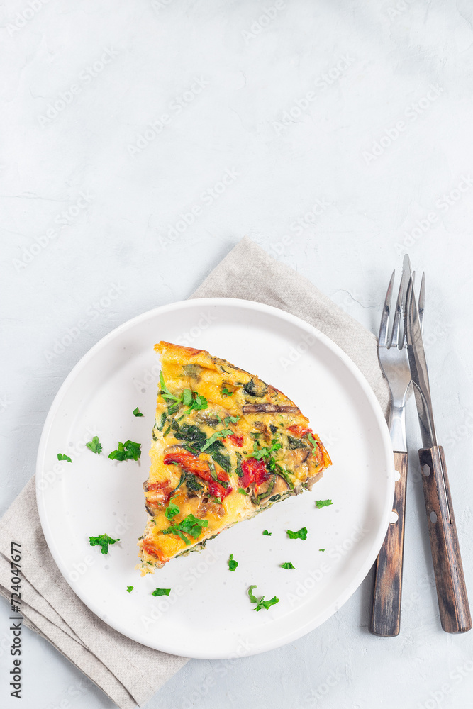 Piece of brunch egg frittata with vegetables on plate, vertical, top view, copy space Piece of brunch egg frittata with vegetables on plate, vertical, top view, copy space