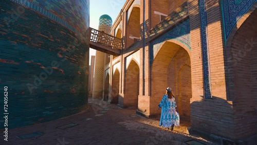 Tourist woman in ethnic dress near Kalta Minar in Ichan Kala of Khiva photo