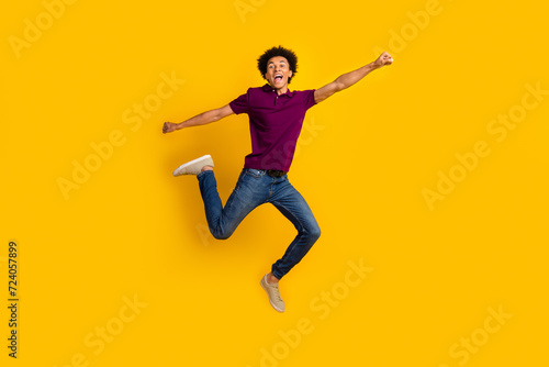 Full length photo of glad optimistic man wear trendy polo raise fist going fast crazy adventure isolated on yellow color background