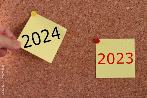 a man's hand pulling out a sticky note. year change from 2023 to 2024. 2024 year consept idea.