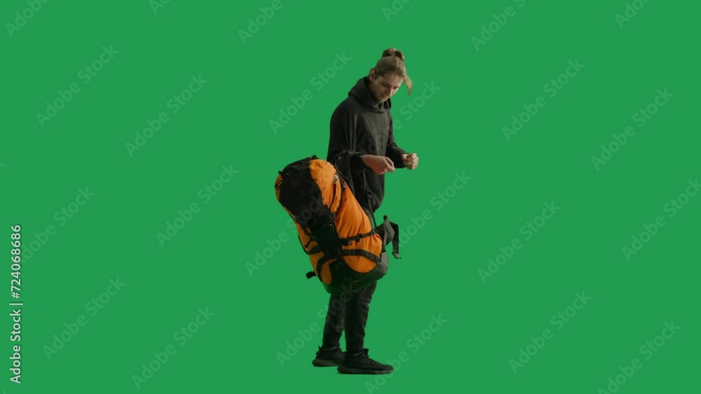 A satisfied male traveler, standing at full height, removes a hiking backpack from his back, taking a break. The man looks around, excitedly saying wow. Male traveler in studio on green screen. A satisfied male traveler, standing at full height, removes a hiking backpack from his back, taking a break. The man looks around, excitedly saying wow. Male traveler in studio on green screen.