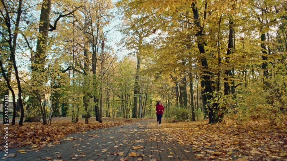 Beautiful Caucasian woman jogging in autumn park. The girl loses weight by doing fitness training, an active sports lifestyle, running on a yellow leaf on a treadmill in the forest. High quality 4k Beautiful Caucasian woman jogging in autumn park. The girl loses weight by doing fitness training, an active sports lifestyle, running on a yellow leaf on a treadmill in the forest. High quality 4k