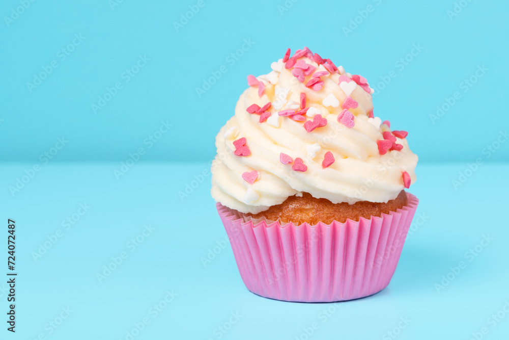 trendy cupcake with sprinkles on blue background, concept of St. Valentines Day, copy space