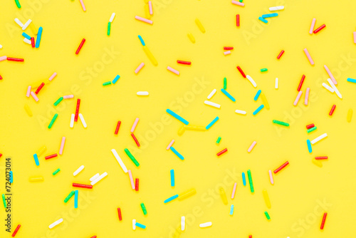 flat lay of colorful sprinkles over yellow background, festive decoration for...