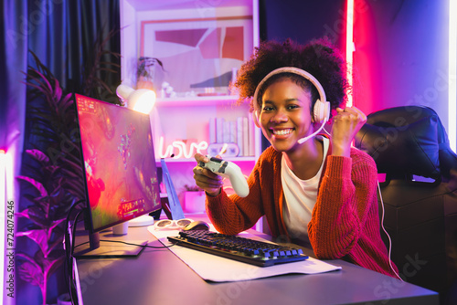 African American girl gaming streamer team winner playing online fighting with Esport wearing headphones in neon lighting room. Talking other players planing strategies to win competitors. Tastemaker.