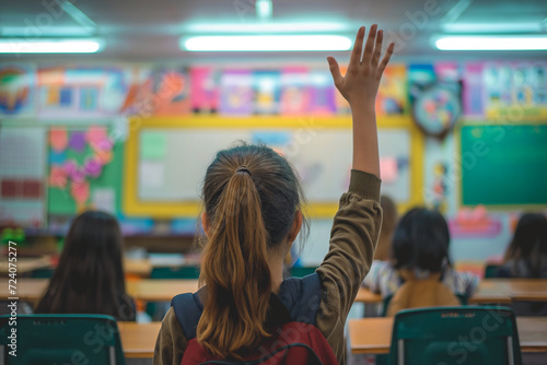 A little girl raising hand to speak in class.