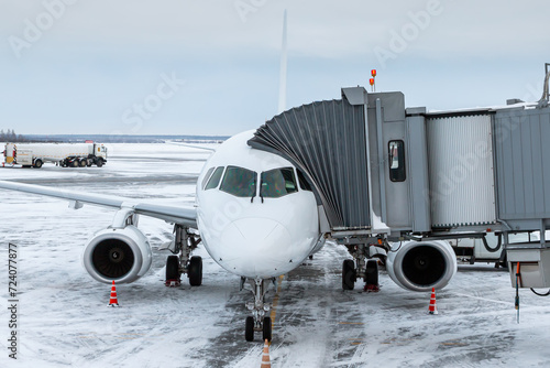 White passenger aircraft at the jetwalk at winter airport apron photo