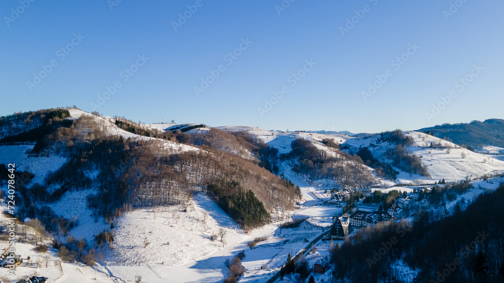 Drone view of Kopaonik Mountain covered with snow in the winter sunset. Aerial view of a scenic forest road on mountainside in wintertime at sunset with snow on Mount Kopaonik