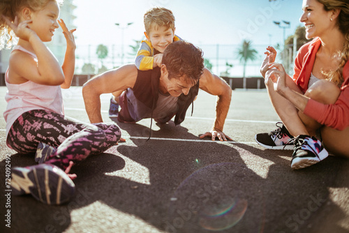 Young family doing push ups and exercising on an outdoor sports court photo