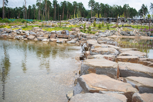 artificial waterfall, stones, pine trees in cloudy weather in summer. Odintsovo district, Moscow region, Russia, Malevich Park is a modern park area that combines outdoor recreation, art and sports. photo