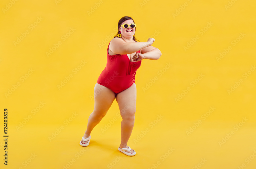 Full body portrait of a funny young happy woman in red swimsuit going on summer holiday trip and having fun on a yellow studio background with copy space. Vacation and travel concept. Full body portrait of a funny young happy woman in red swimsuit going on summer holiday trip and having fun on a yellow studio background with copy space. Vacation and travel concept.