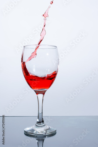 Red wine poured into a glass on a white background