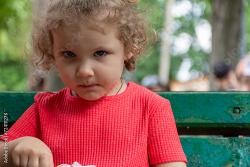 Little girl in red t-shirt looking sternly forward