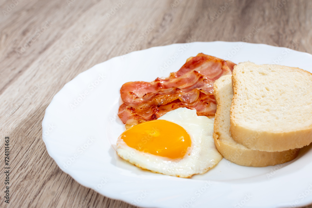 Fried bacon with egg and bread on a white plate Fried bacon with egg and bread on a white plate