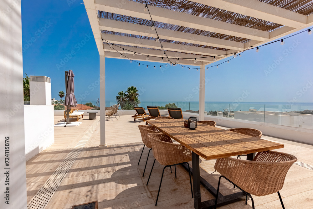 Fototapeta premium a luxury rooftop terrace with large wooden table and mediterranean sea views 
