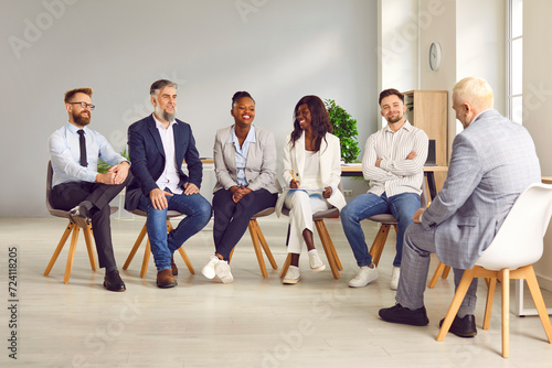 Multiracial business people having business training in office. Happy multiethnic employees sitting in circle on chairs during informal brainstorming, discussing, sharing ideas. Team building activity