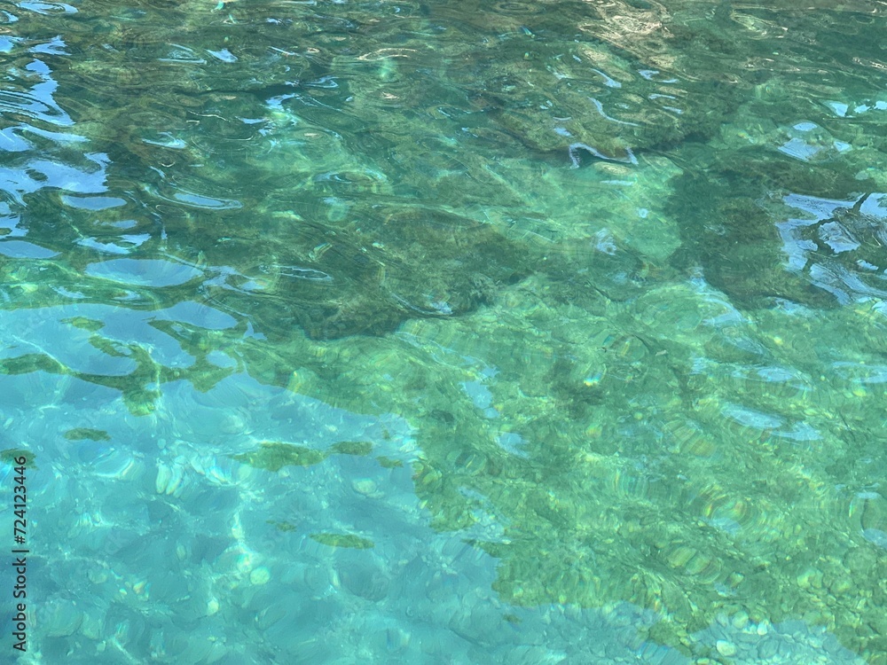 Glittering clear water surface with pebbles at the bottom