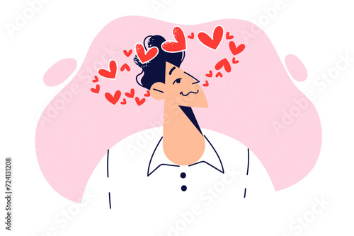 Man in love feels dizzy due to romantic feelings, stands with hearts flying on top of head