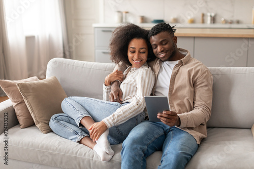 Happy black spouses have video call chatting by tablet indoor