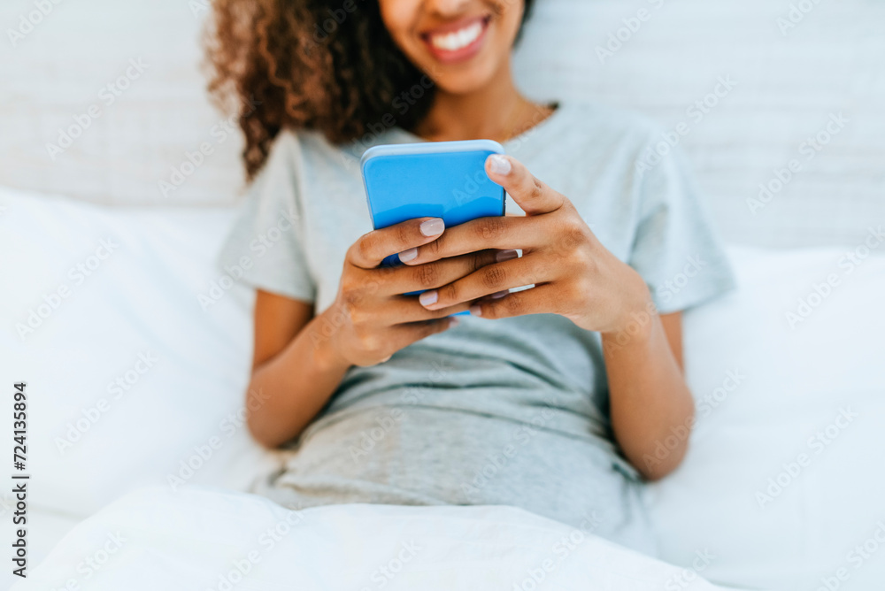 Close-up of woman's hands with mobile phone in bed