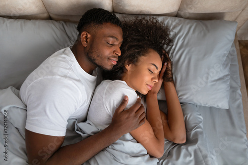 Top view of african american couple sleeping in bed embracing