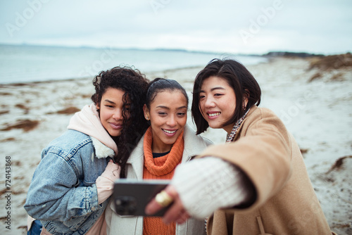 Young and diverse group of female friends taking a selfie on a sandy beach photo