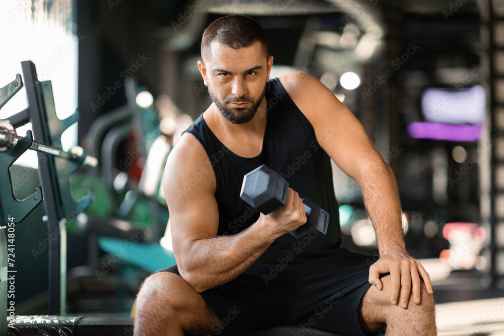 Young Muscular Man Doing Exercises With Dumbbell In Modern Gym Young Muscular Man Doing Exercises With Dumbbell In Modern Gym