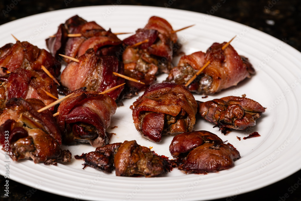Cooked chicken liver wrapped with bacon. Roasted liver kebabs with on a white plate. Cooked chicken liver wrapped with bacon. Roasted liver kebabs with on a white plate.