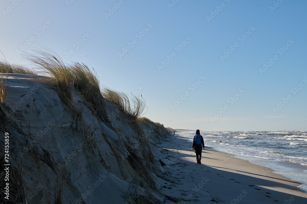 Spacer w sztormową, słoneczną pogodę. Brzeg morza przesunął się. Morze zabrało dużą część plaży. Kobieta spaceruje i robi zdjęcia.