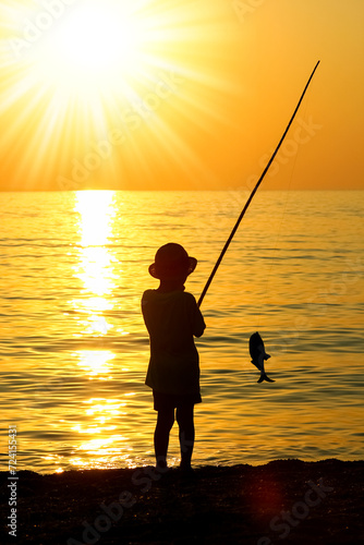 A happy child fishing by the sea silhouette