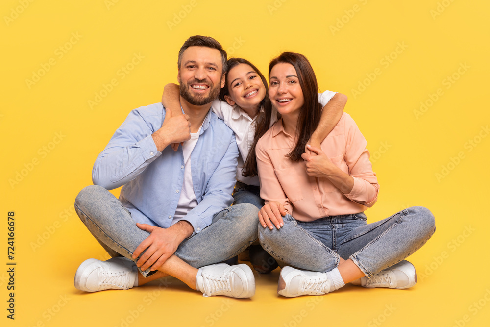 Happy European Family Embracing Sitting Together Against Yellow Studio Background