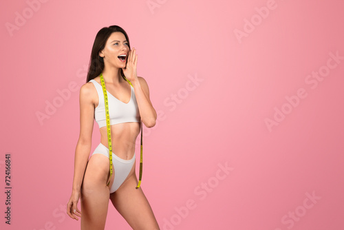 Pensive millennial caucasian woman in white underwear with measuring tape screaming © Prostock-studio
