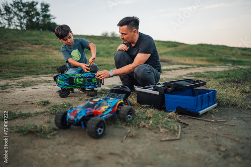 Quality playtime of father and his son outdoors, fixing toy race cars.