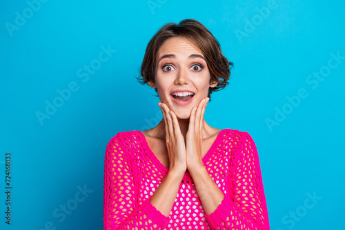Photo of impressed sweet woman wear knitted neon shirt hands arms cheeks cheekbones isolated blue color background