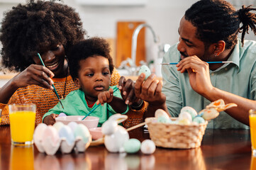 African american family having fun decorating easter eggs together at home
