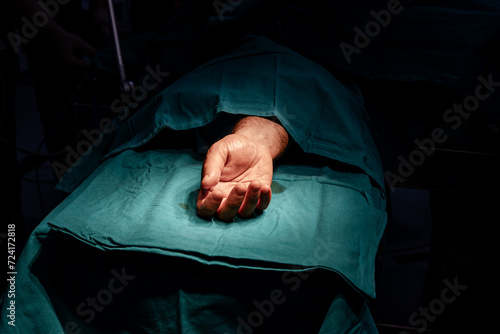 Patient's hand on operation table ready for surgery in a sterile operating room.