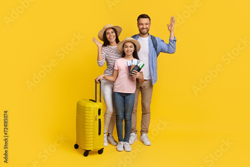 Happy caucasian family with suitcases and travel documents posing on yellow background photo