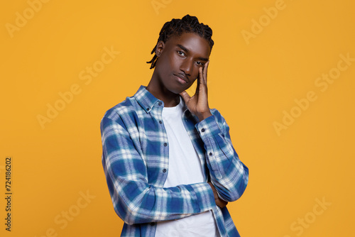 Pensive young black man touching face and looking at camer photo