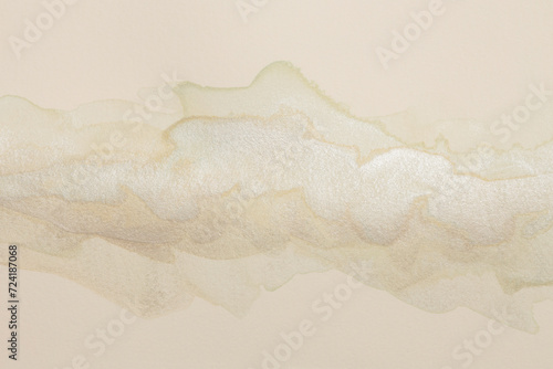 Beige, gold, silver ink watercolor smoke flow stain blot on wet paper grain texture background. © Liliia